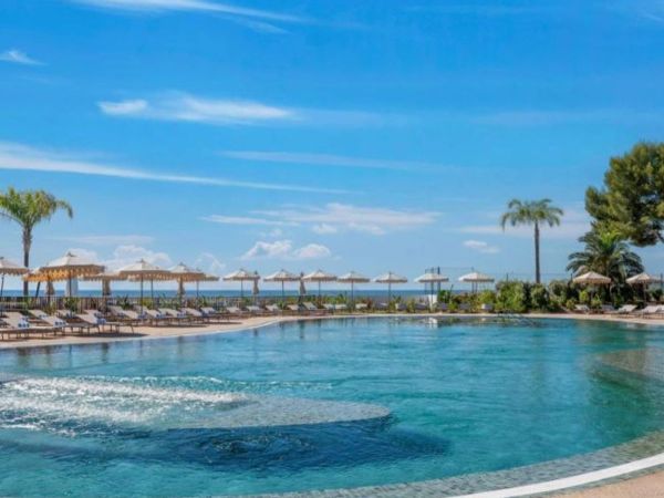 Piscine lagon ext�rieure avec transats, parasols et palmiers au Marina Baie des Anges h�tel