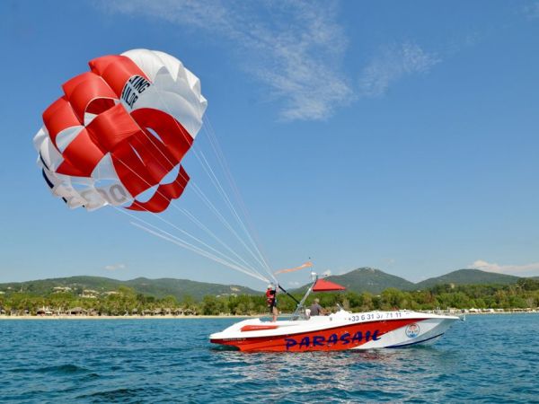 Bateau de parachute ascensionnel tractant une voile rouge et blanche au large de Marina Baie des Anges